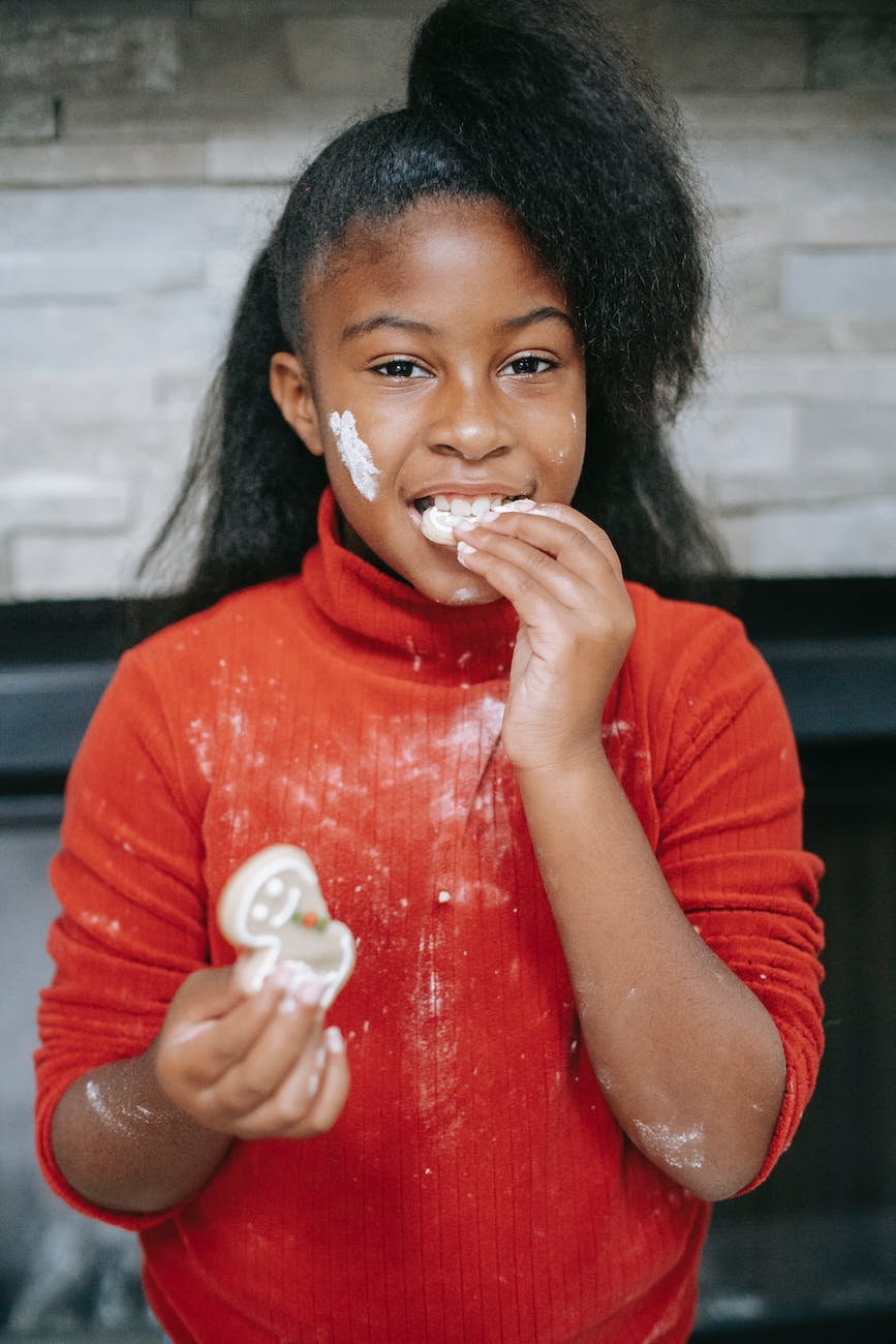 charming dirty black girl eating gingerbread cookie during christmas holiday